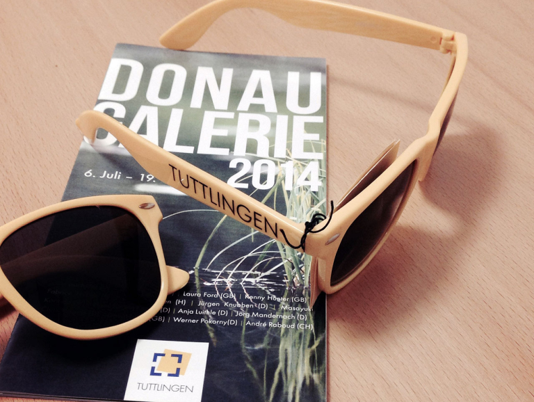 Die gelbe Brille mit dem Flyer der Donaugalerie